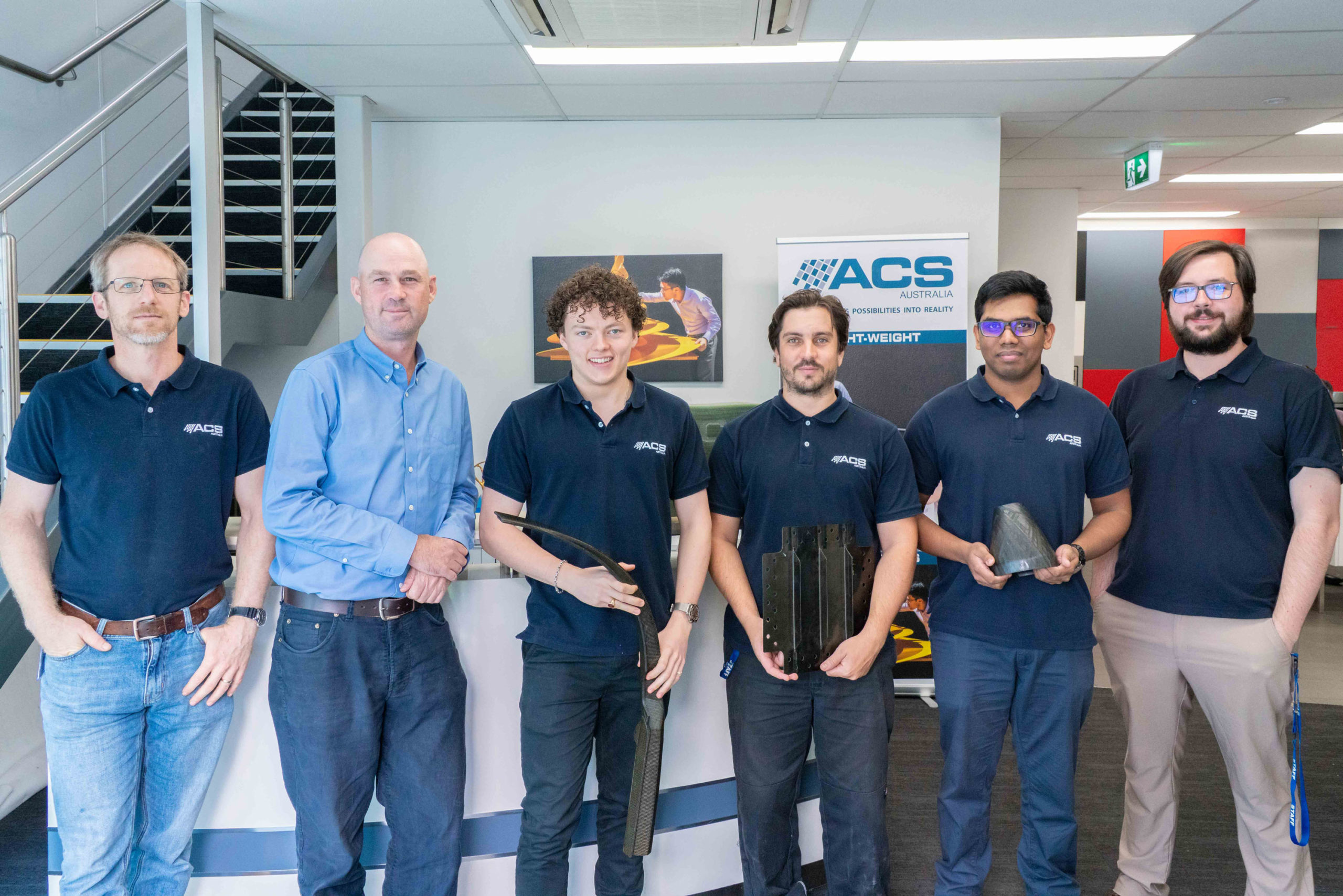 (L-R) Group photo of Defence Industry Internship Program (DIIP) Interns and managers Johannes Straub, Mat Stoessiger, Kai Farrer, Nic Rayner, Shevaan Leitan and George Frake III at Advanced Composite Structures Australia (ACS-A)